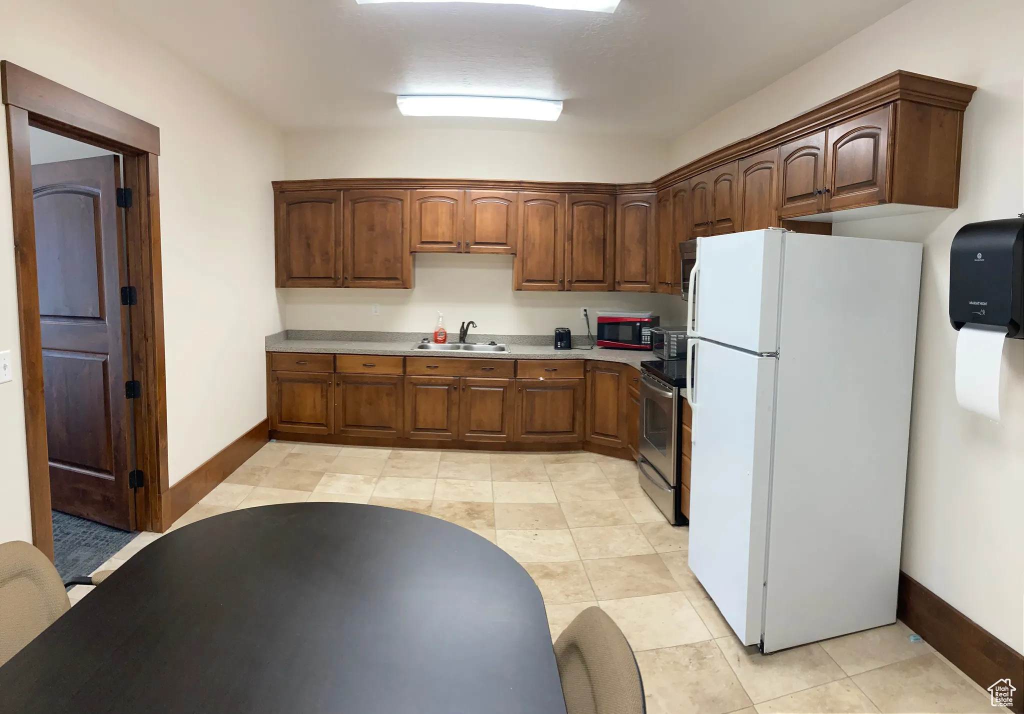 Kitchen with freestanding refrigerator, stainless steel electric stove, light countertops, and light tile patterned floors