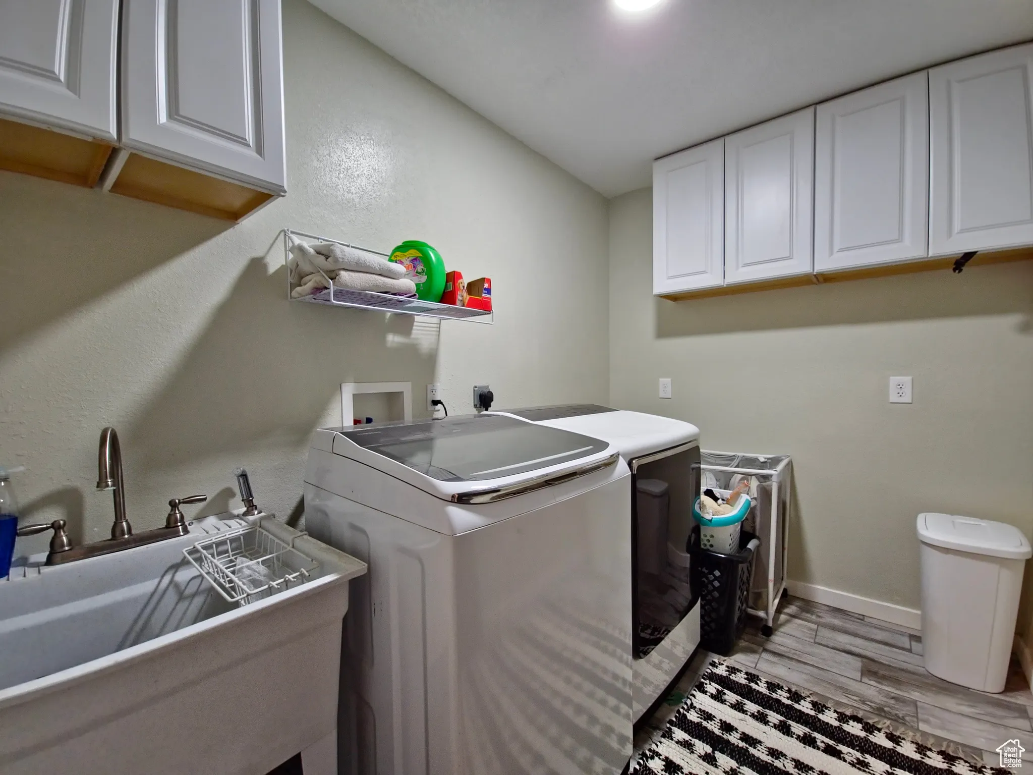 Laundry area with cabinet space, washing machine and dryer, and light wood-style floors