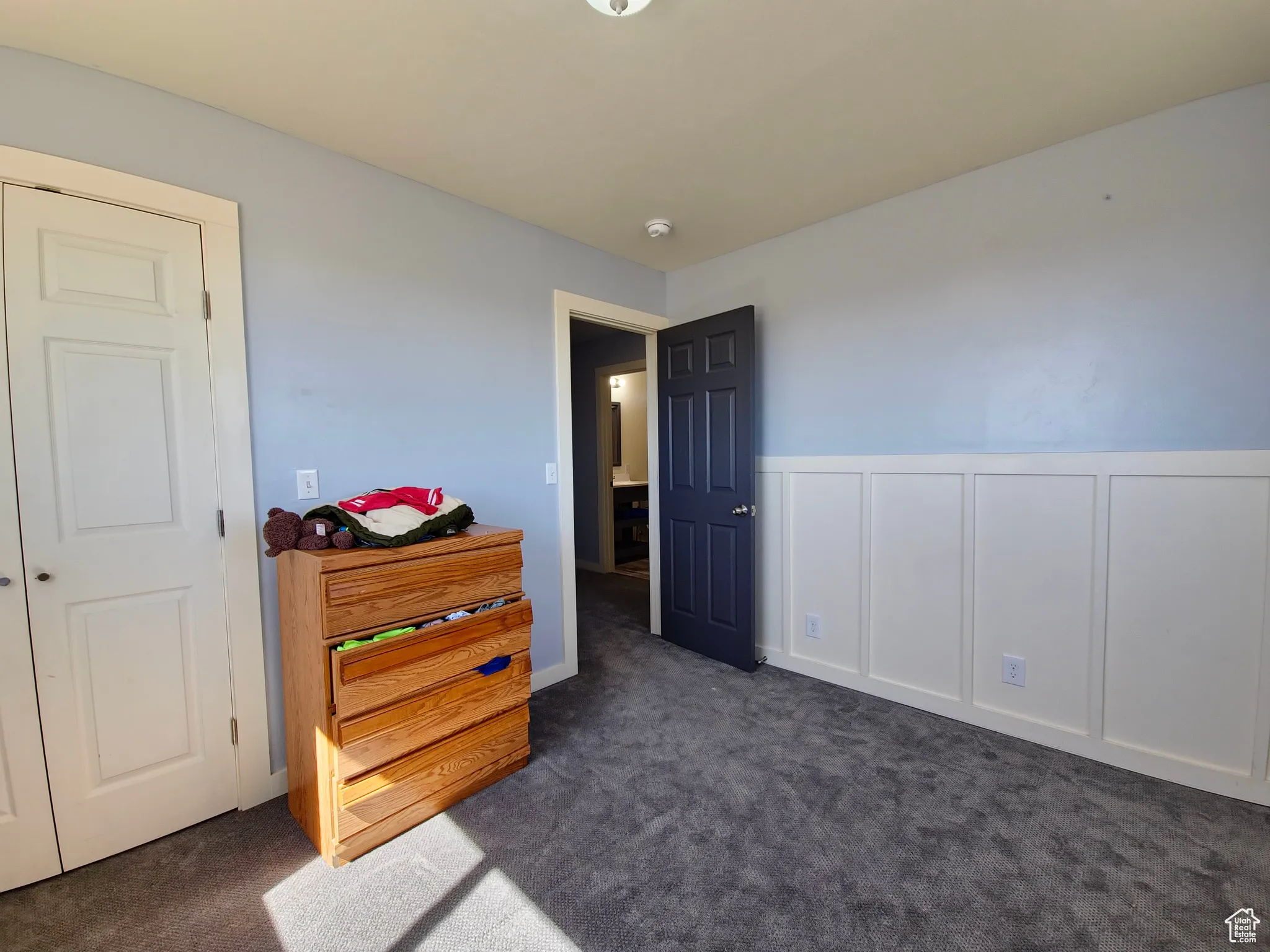 Bedroom featuring carpet floors, a decorative wall, and wainscoting