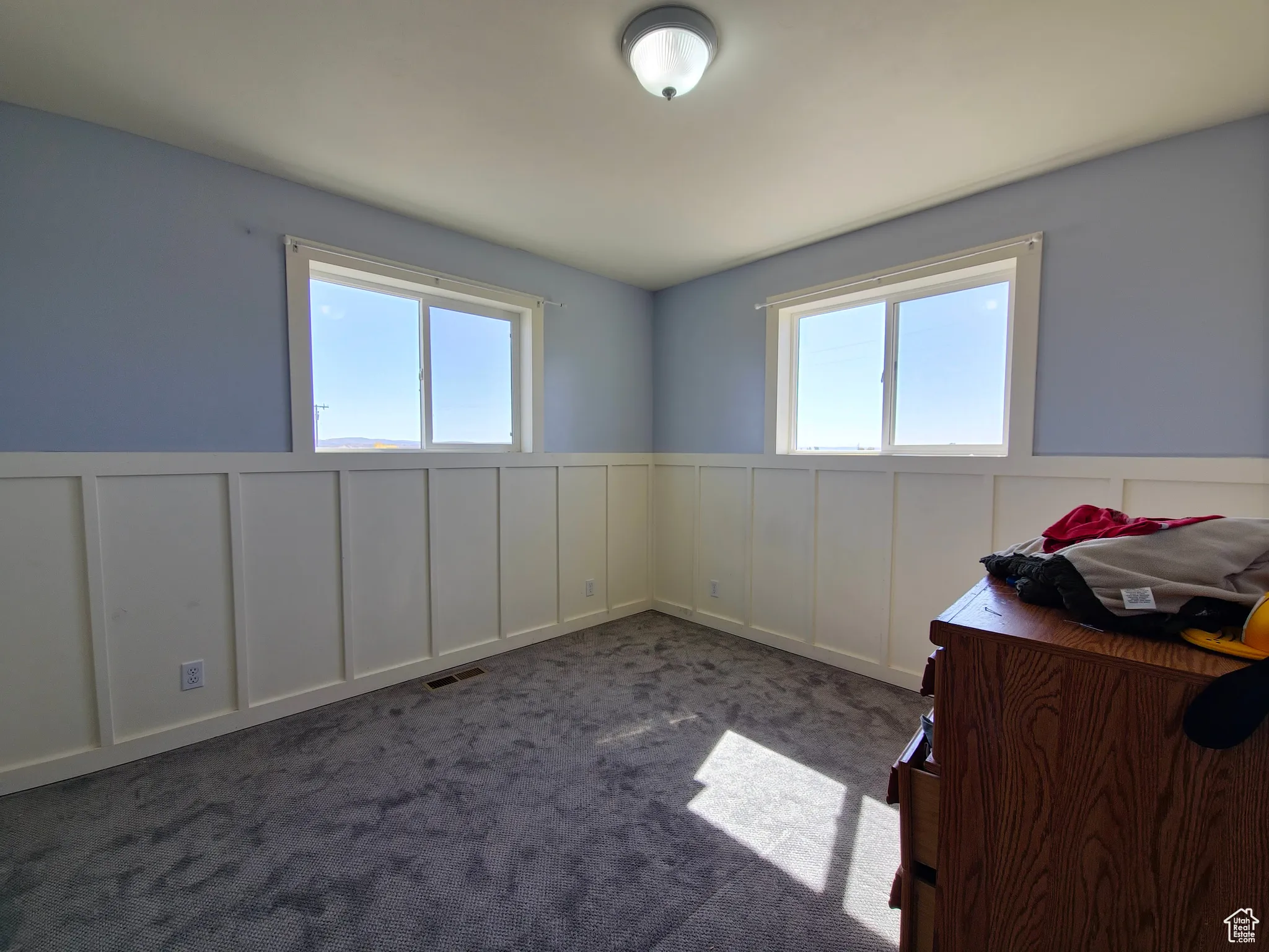 Carpeted spare room with a decorative wall, a wainscoted wall, and plenty of natural light