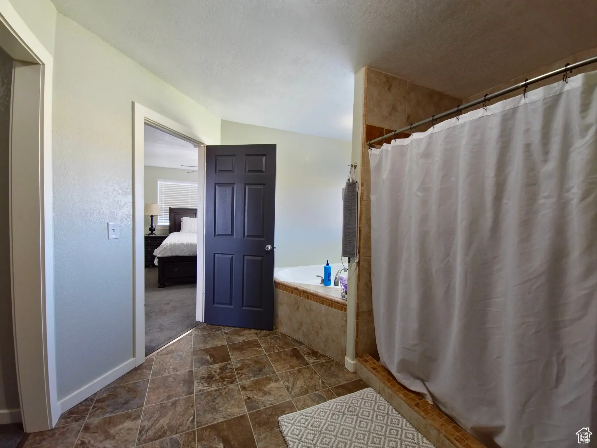Bathroom with a stall shower, a garden tub, ensuite bath, and dark stone finish flooring