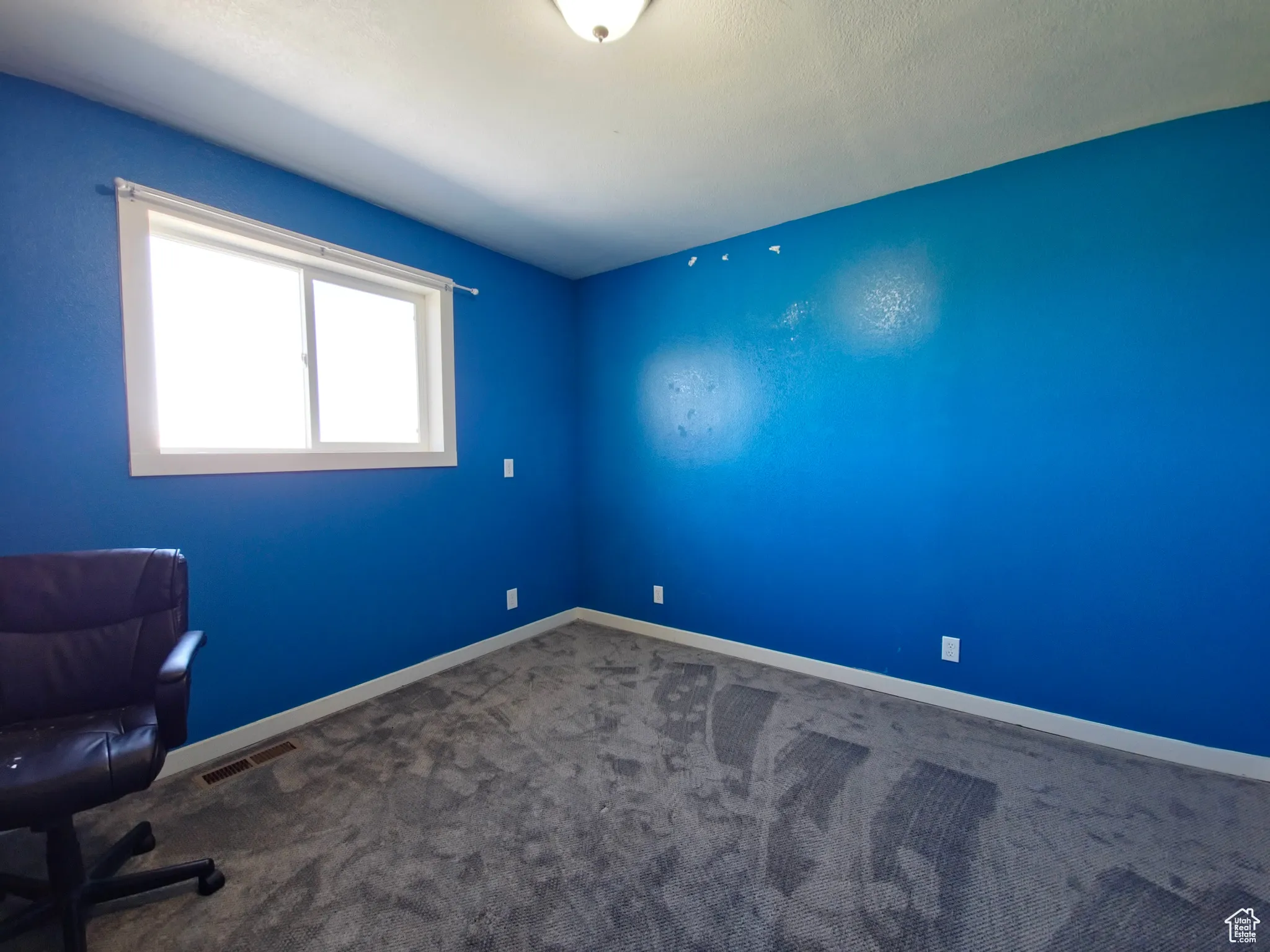 Unfurnished office with dark colored carpet and baseboards