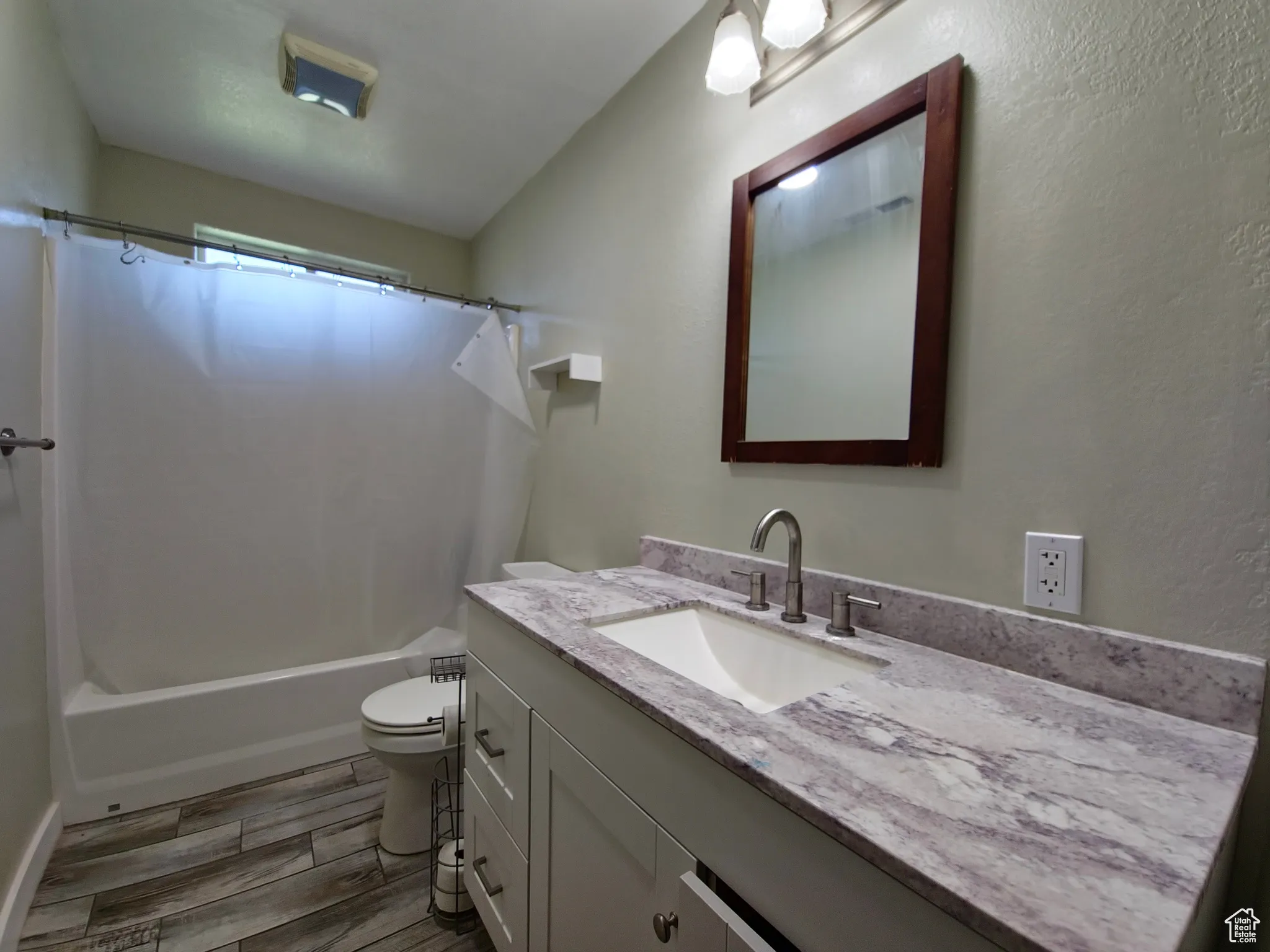 Bathroom with shower / tub combo, vanity, wood finish floors, and a textured wall