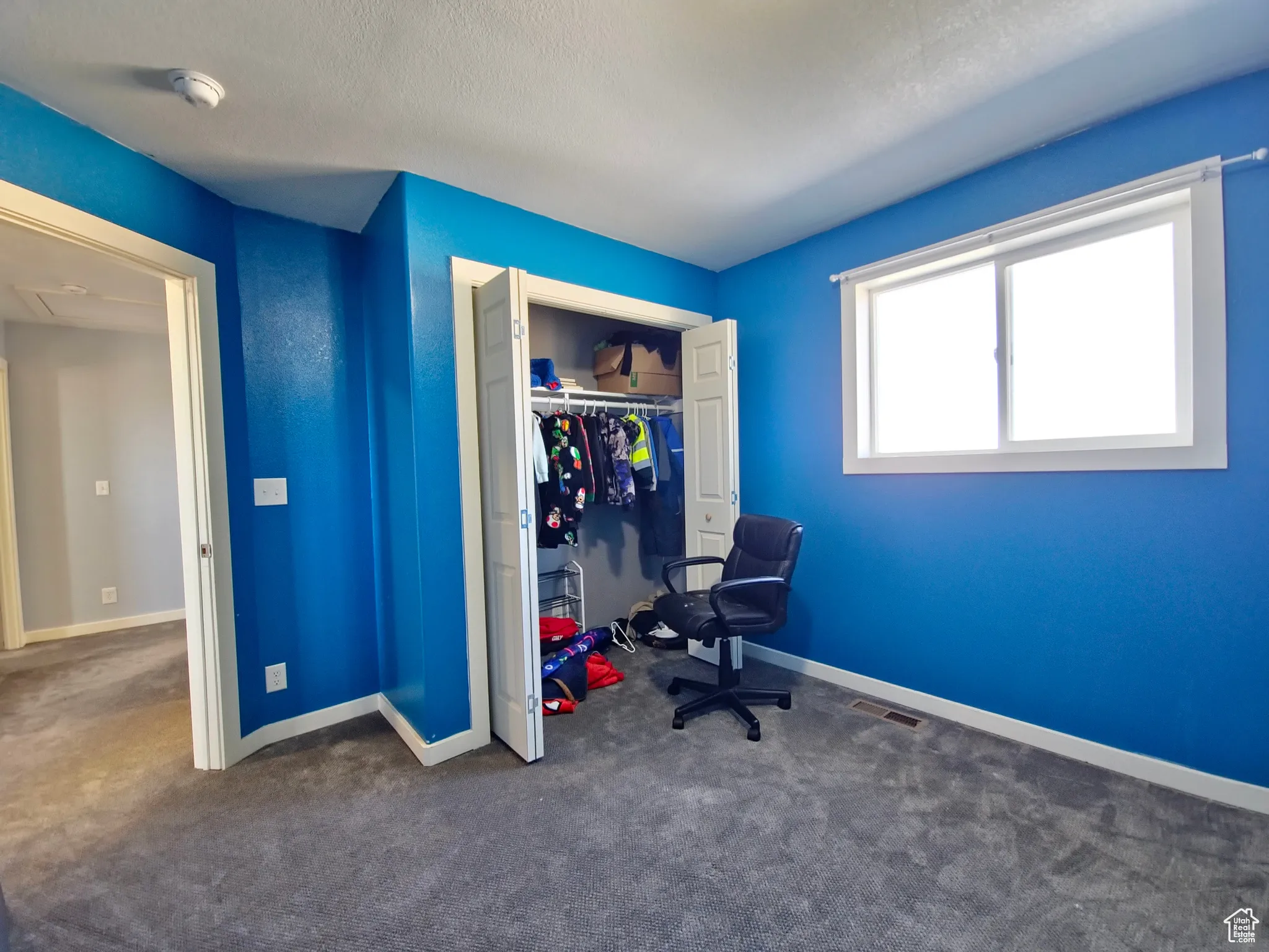 Bedroom with dark carpet, a closet, and a textured ceiling