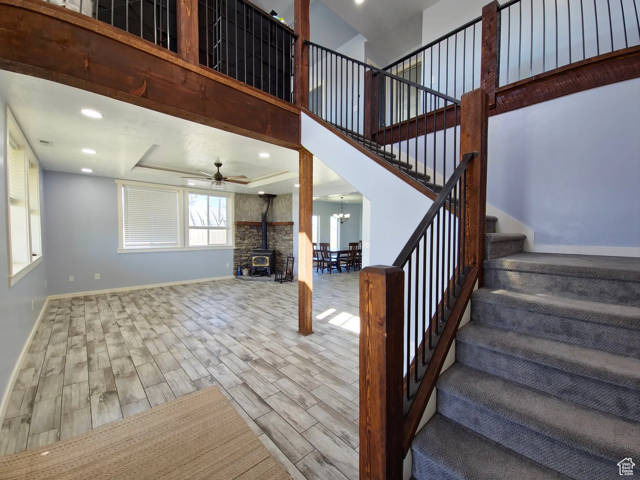 Stairway featuring a wood stove, wood finish floors, a chandelier, a high ceiling, and a tray ceiling
