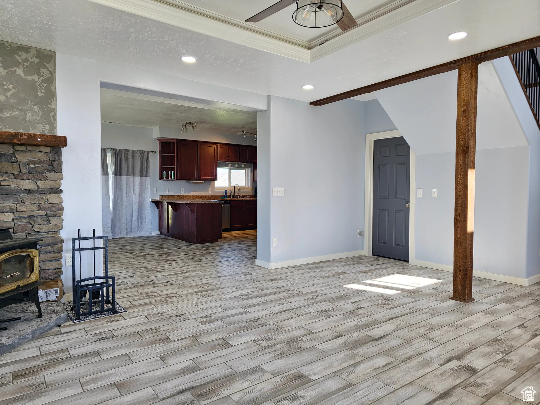 Unfurnished living room featuring recessed lighting, a wood stove, light wood-style flooring, crown molding, and a ceiling fan