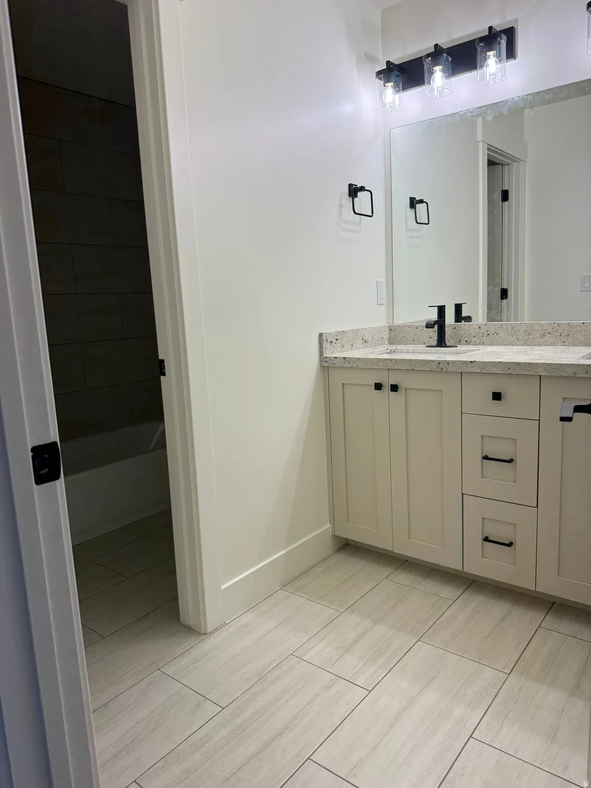 Bathroom vanity with light-toned countertop, dual rectangular sinks, and matte black fixtures