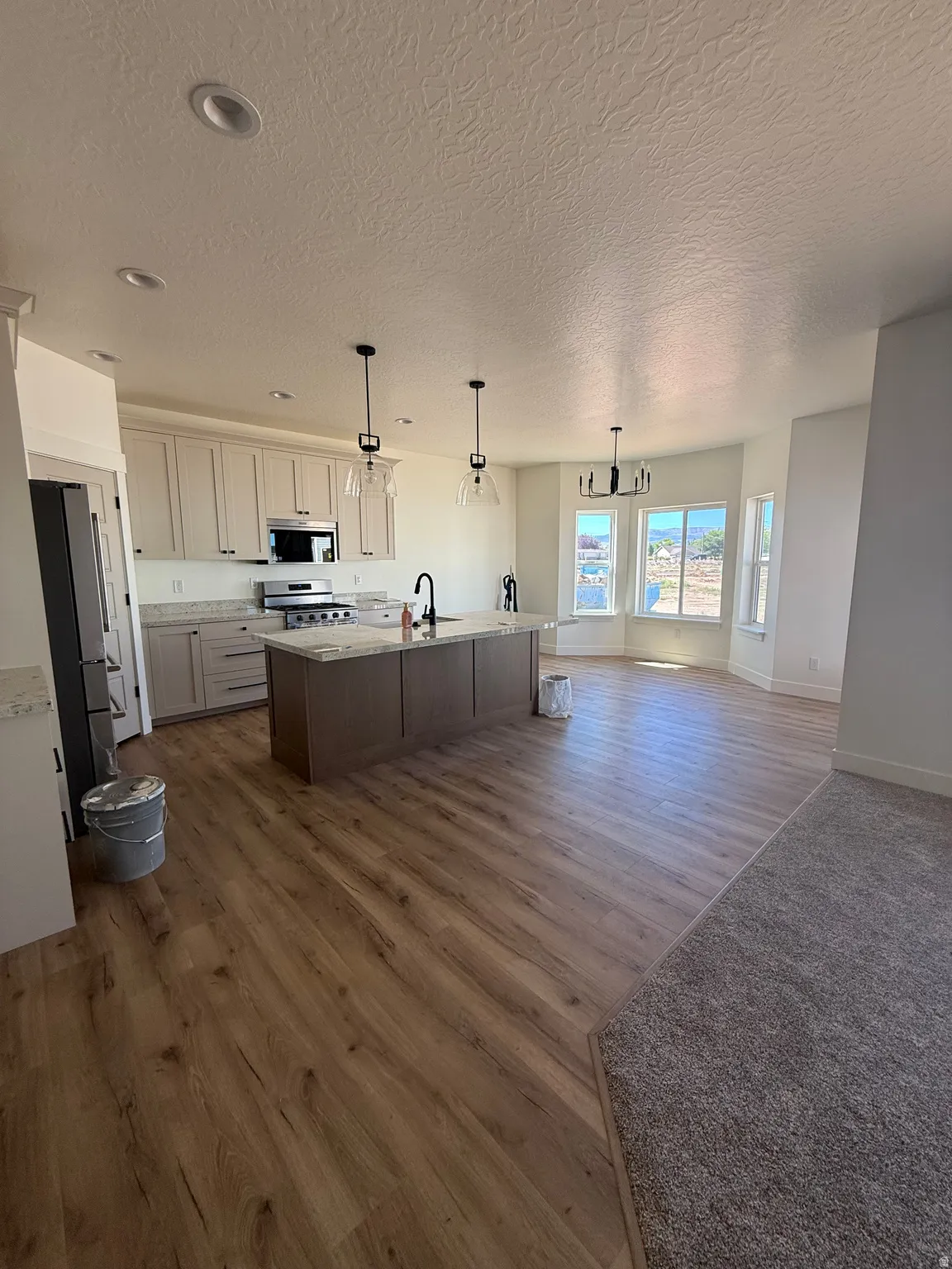 Spacious kitchen featuring light-toned cabinetry, a central island with a contrasting base, stainless steel appliances, and recessed lighting