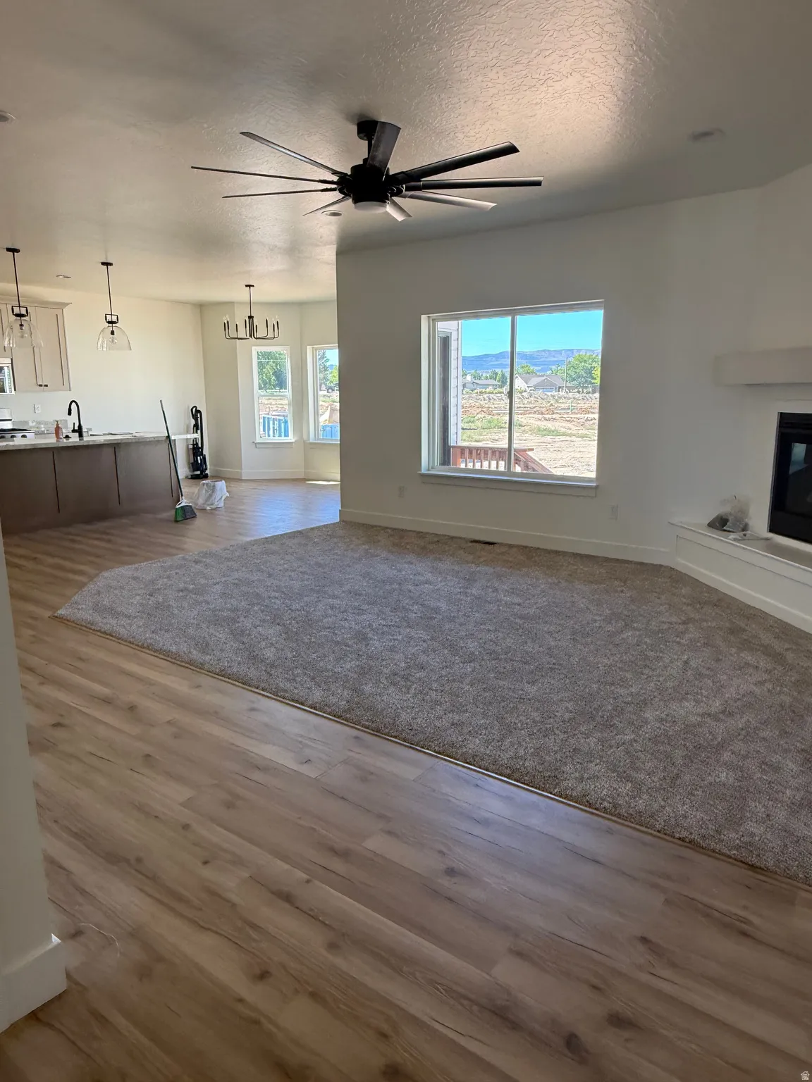 Open-concept living area featuring wood-finish flooring, a contemporary ceiling fan, and a large window