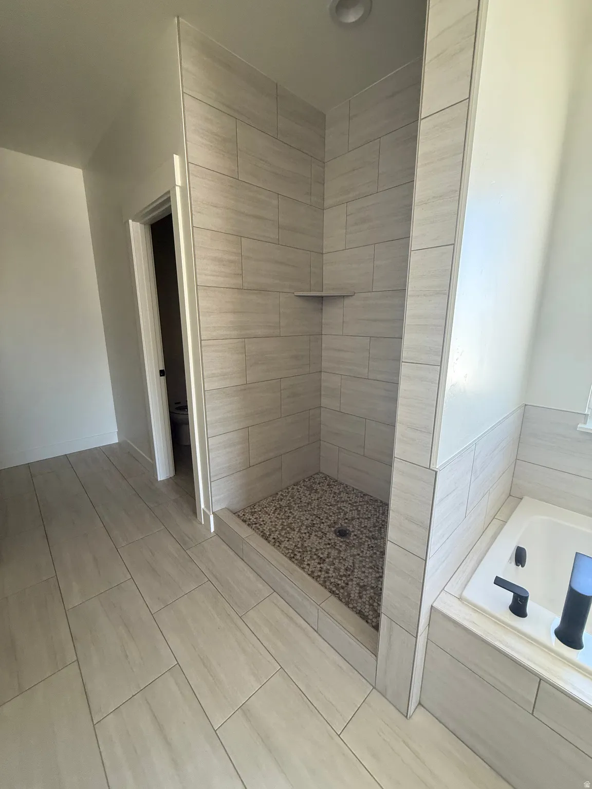 Walk-in shower with tile surround, pebble floor, and integrated shelf