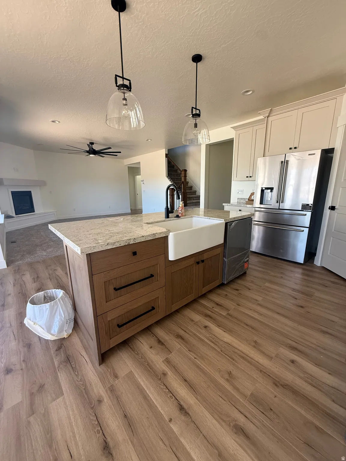 Kitchen island with a farmhouse sink, quartz countertop, and wood-finish flooring