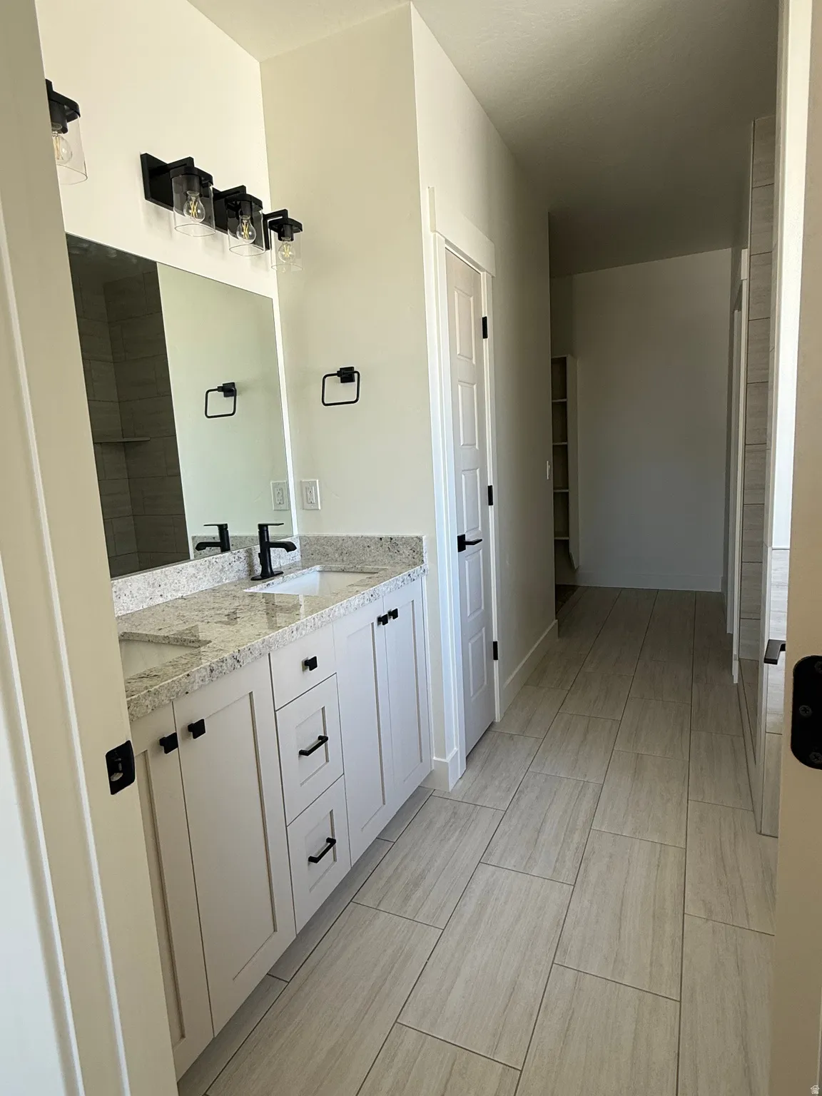 Dual vanity with a speckled countertop, undermount sinks, and matte black fixtures