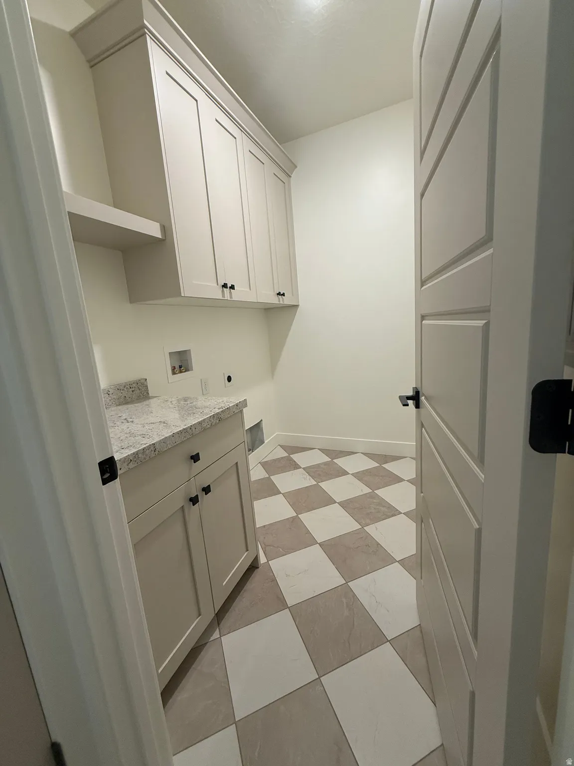 Laundry area featuring checkerboard tile flooring, built-in cabinetry with crown molding, a countertop, and a dedicated shelf