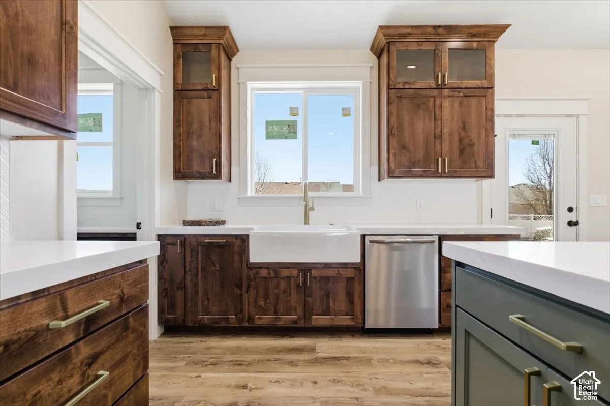 Kitchen with glass fronted cabinets, stainless steel dishwasher, healthy amount of natural light, and two tone cabinets