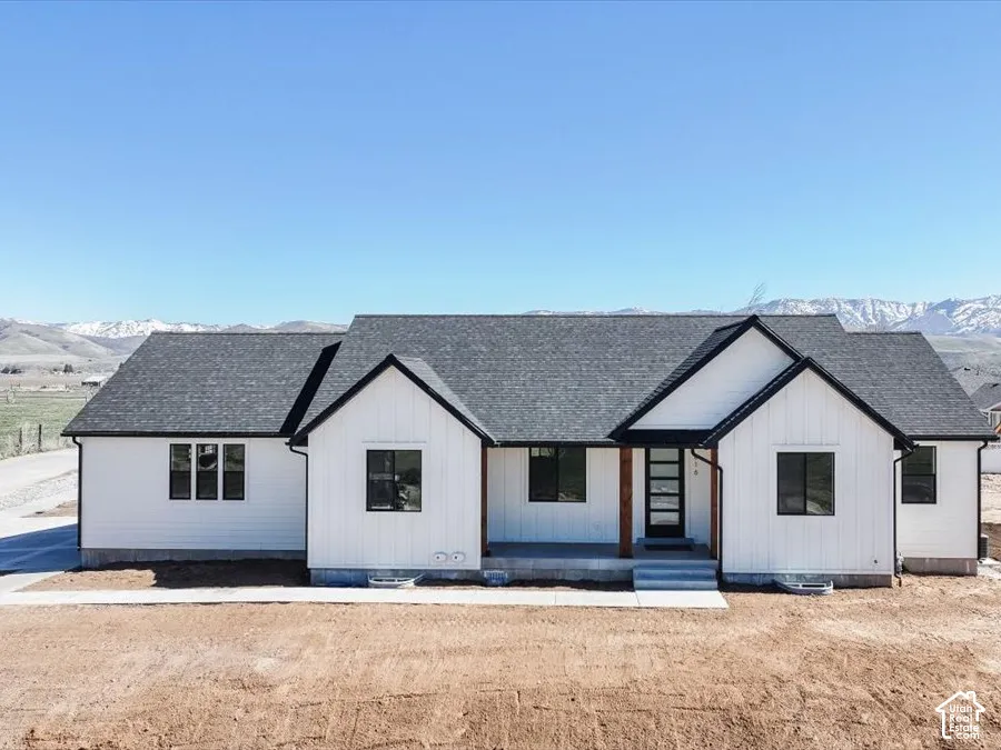 Modern farmhouse style home with a mountain view, a shingled roof, and covered porch