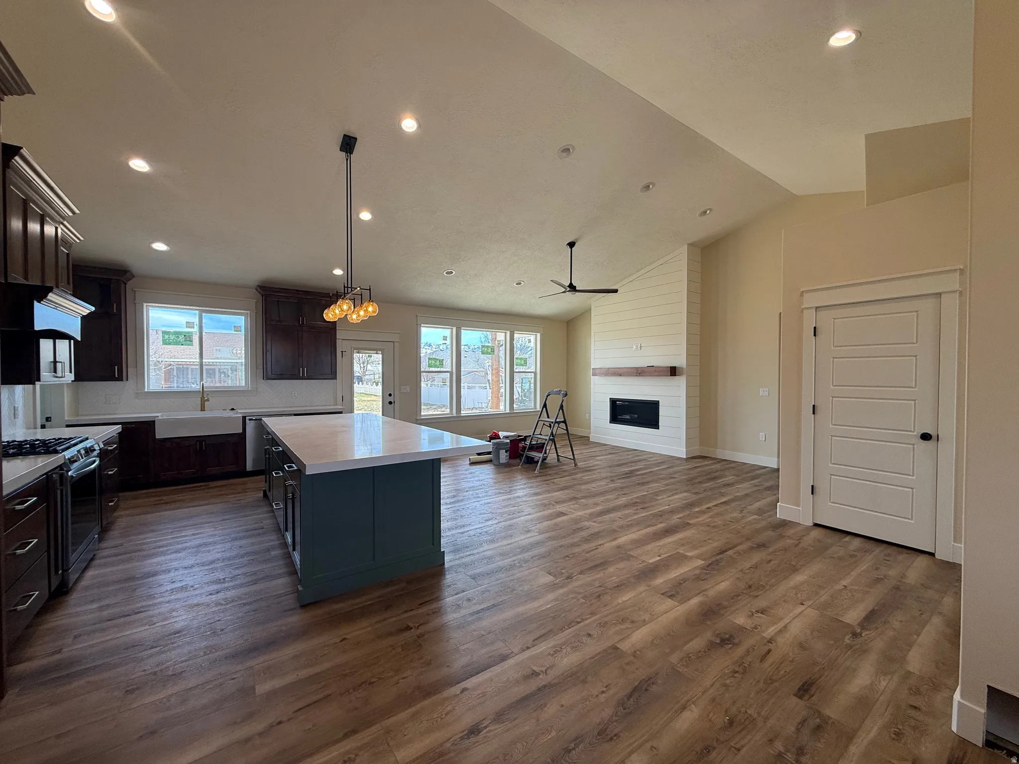 Kitchen with open floor plan, lofted ceiling, a kitchen island, stainless steel gas stove, and a large fireplace