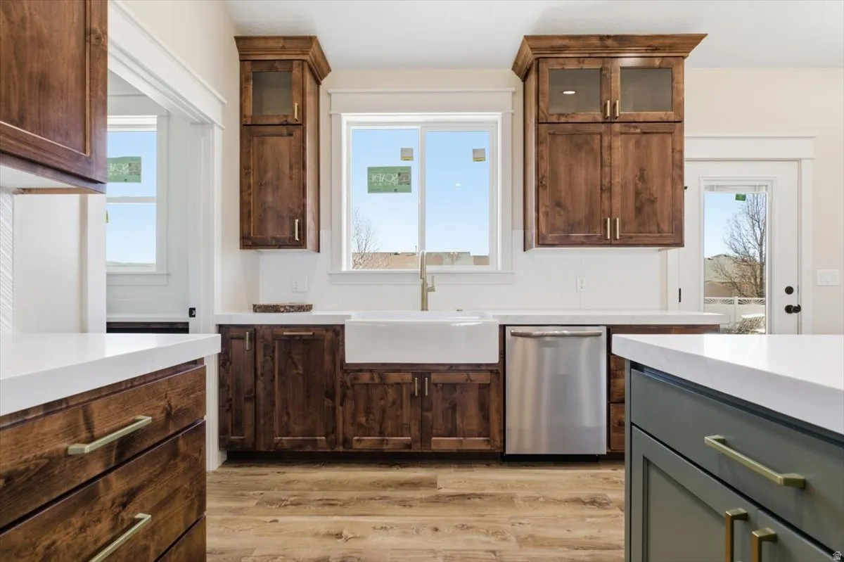 Kitchen with glass fronted cabinets, stainless steel dishwasher, healthy amount of natural light, and two tone cabinets