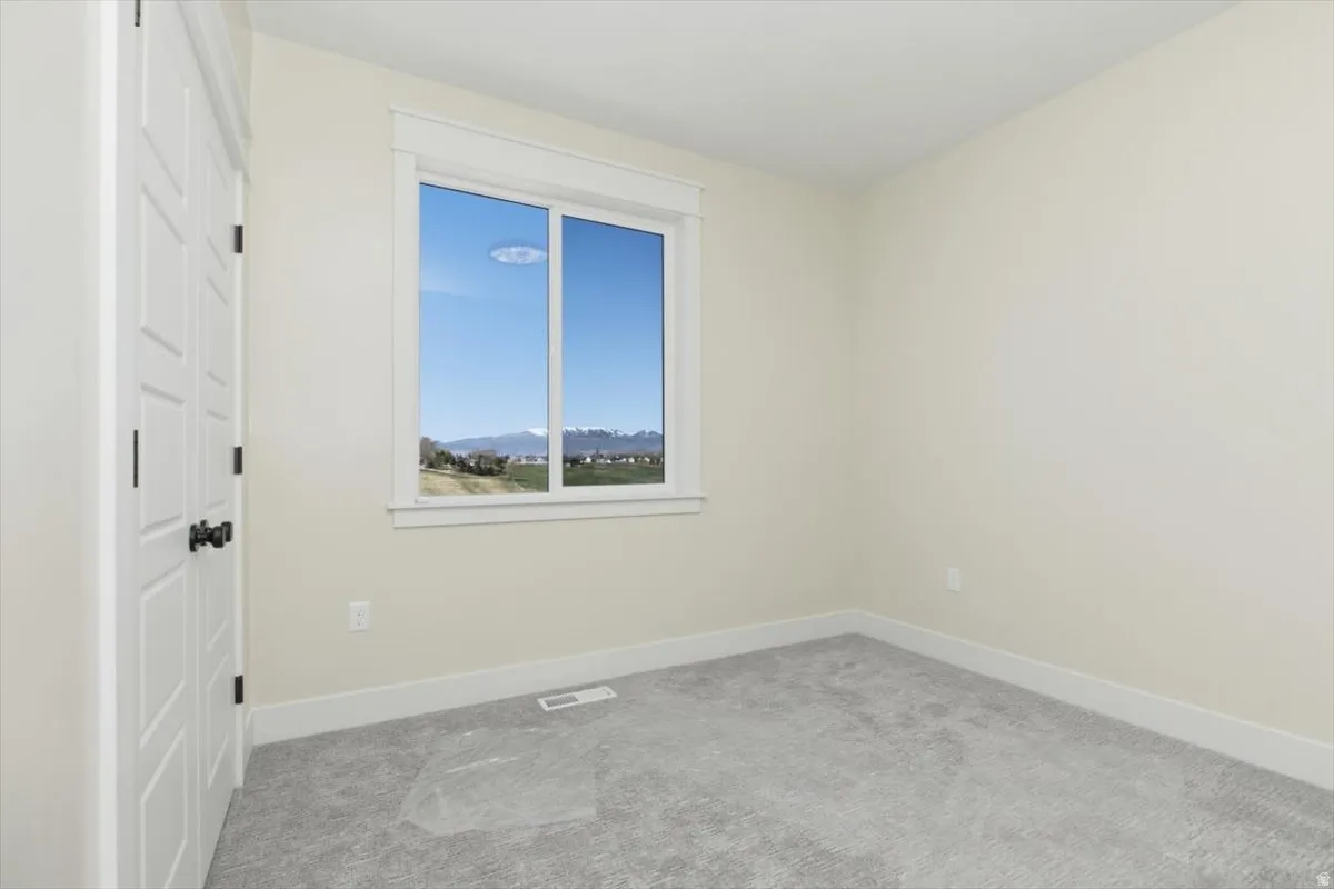 Empty room with light carpet and baseboards