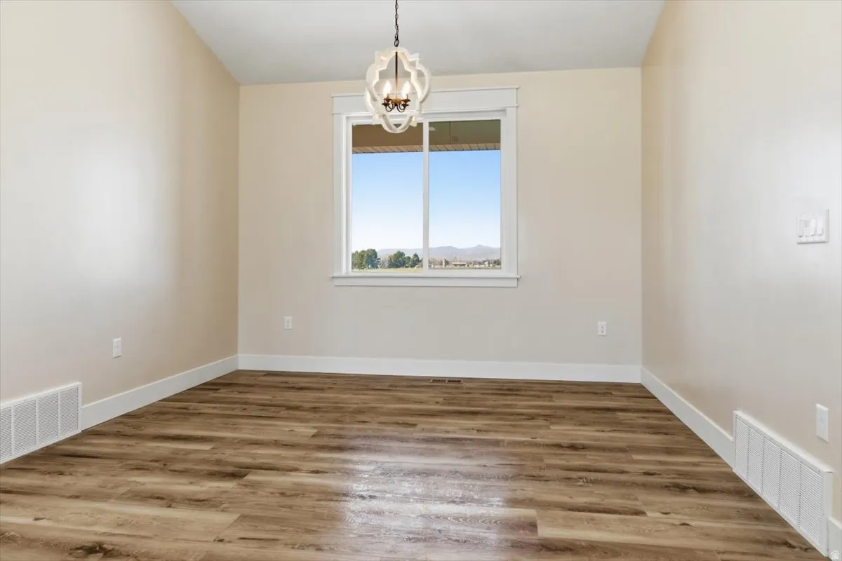 Spare room featuring light wood finished floors and a chandelier