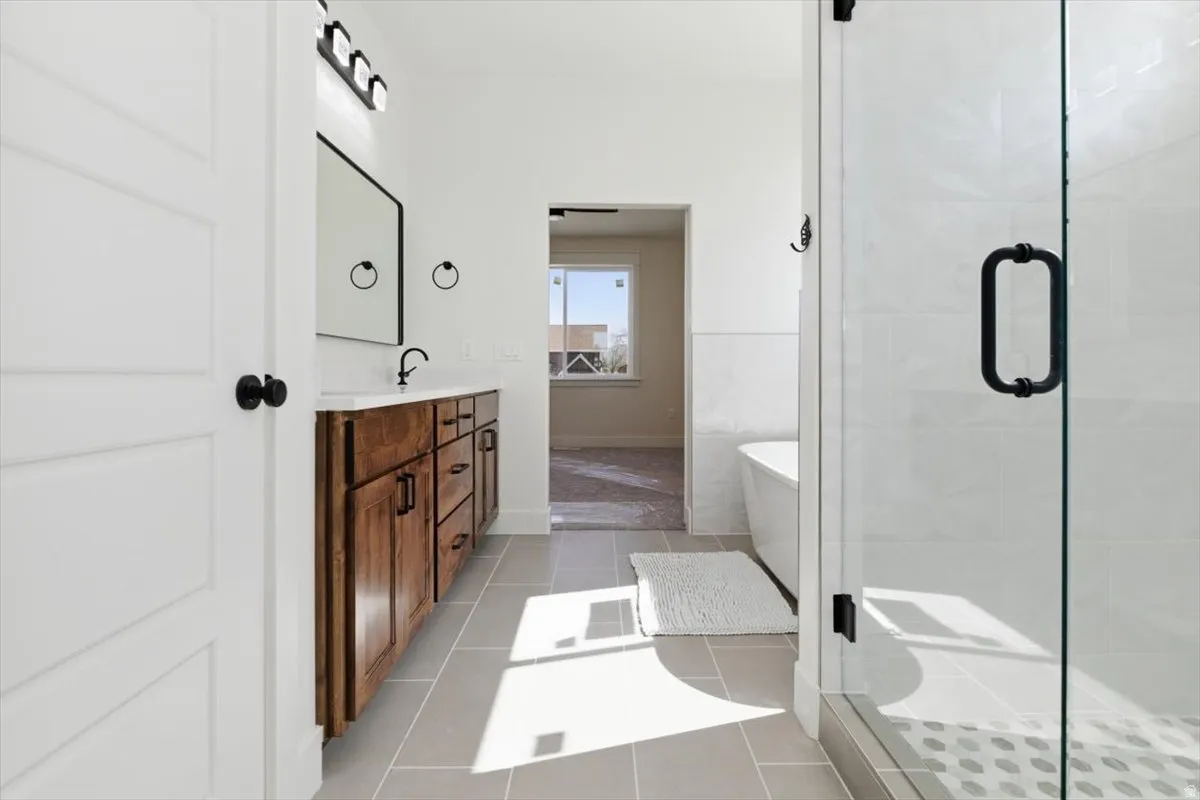 Full bathroom with double vanity, a soaking tub, a stall shower, and light tile patterned flooring