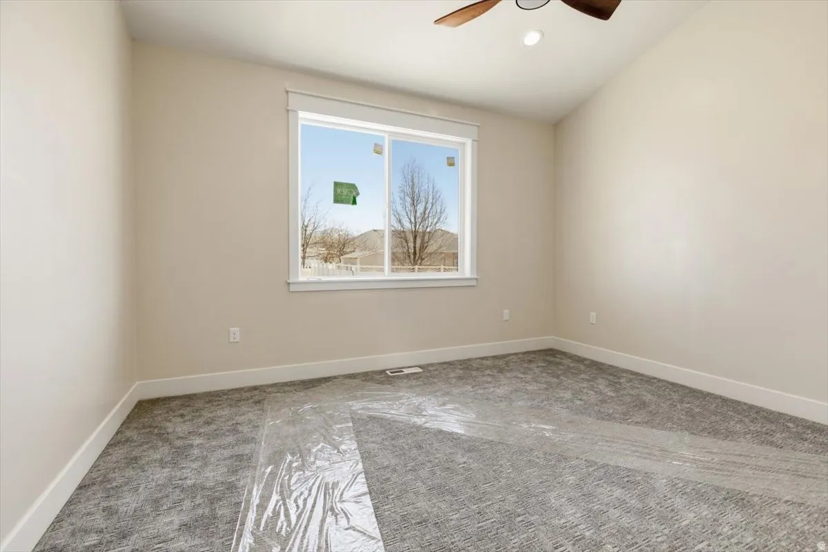 Spare room with light colored carpet, a ceiling fan, and lofted ceiling
