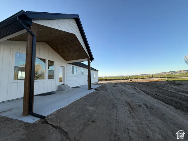 View of side of property featuring a patio area, board and batten siding, entry steps, and a mountain view