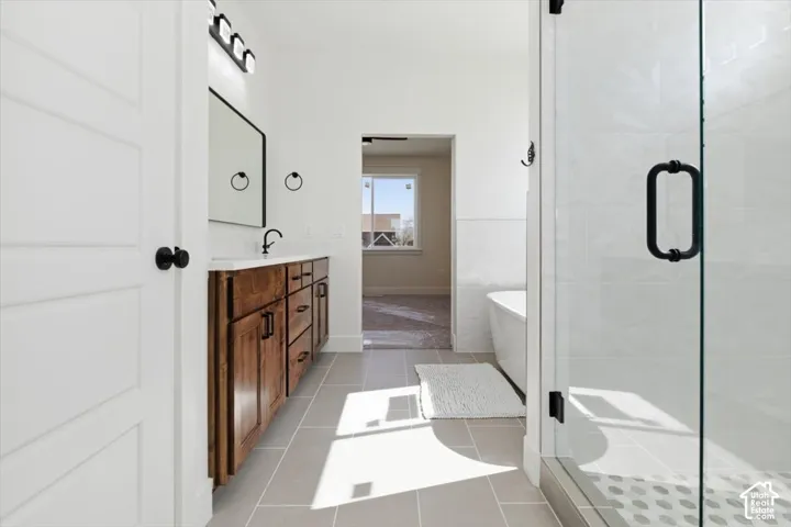 Full bathroom with double vanity, a soaking tub, a stall shower, and light tile patterned flooring