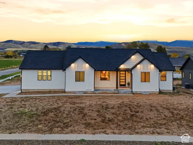 Contemporary residence featuring a crisp white siding exterior, dark shingled roof, recessed covered entryway, and mountainous scenery