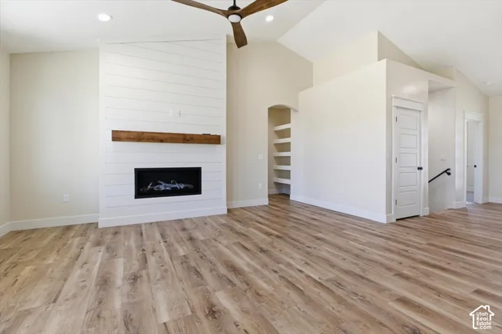 Unfurnished living room featuring vaulted ceiling, light wood-style floors, recessed lighting, a fireplace, and ceiling fan