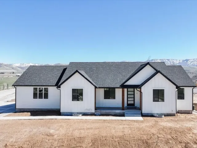 Modern farmhouse style home with a mountain view, a shingled roof, and covered porch