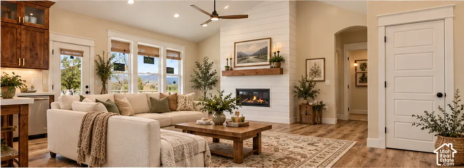 Vaulted ceiling with a ceiling fan, gas fireplace with a wood mantle, shiplap accent wall, LVP with wood-finish look flooring, and recessed lighting