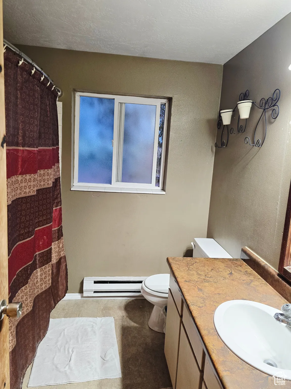 Full bath featuring vanity, a baseboard heating unit, curtained shower, and a textured ceiling