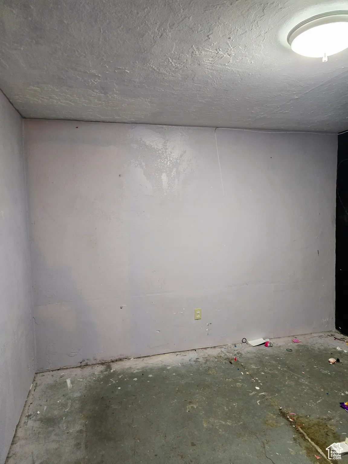 Empty room featuring a textured ceiling and unfinished concrete floors