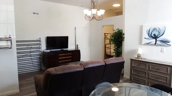 Living area with dark wood-style floors and a chandelier