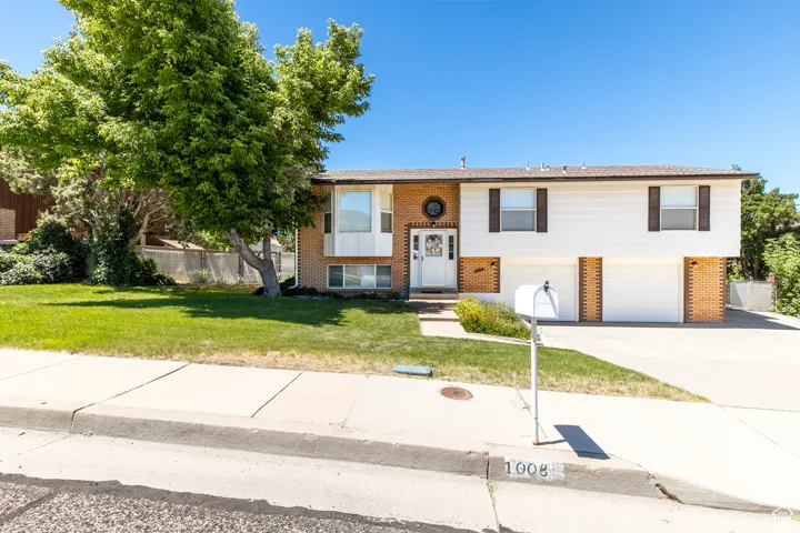 Raised ranch with brick siding, driveway, and a garage