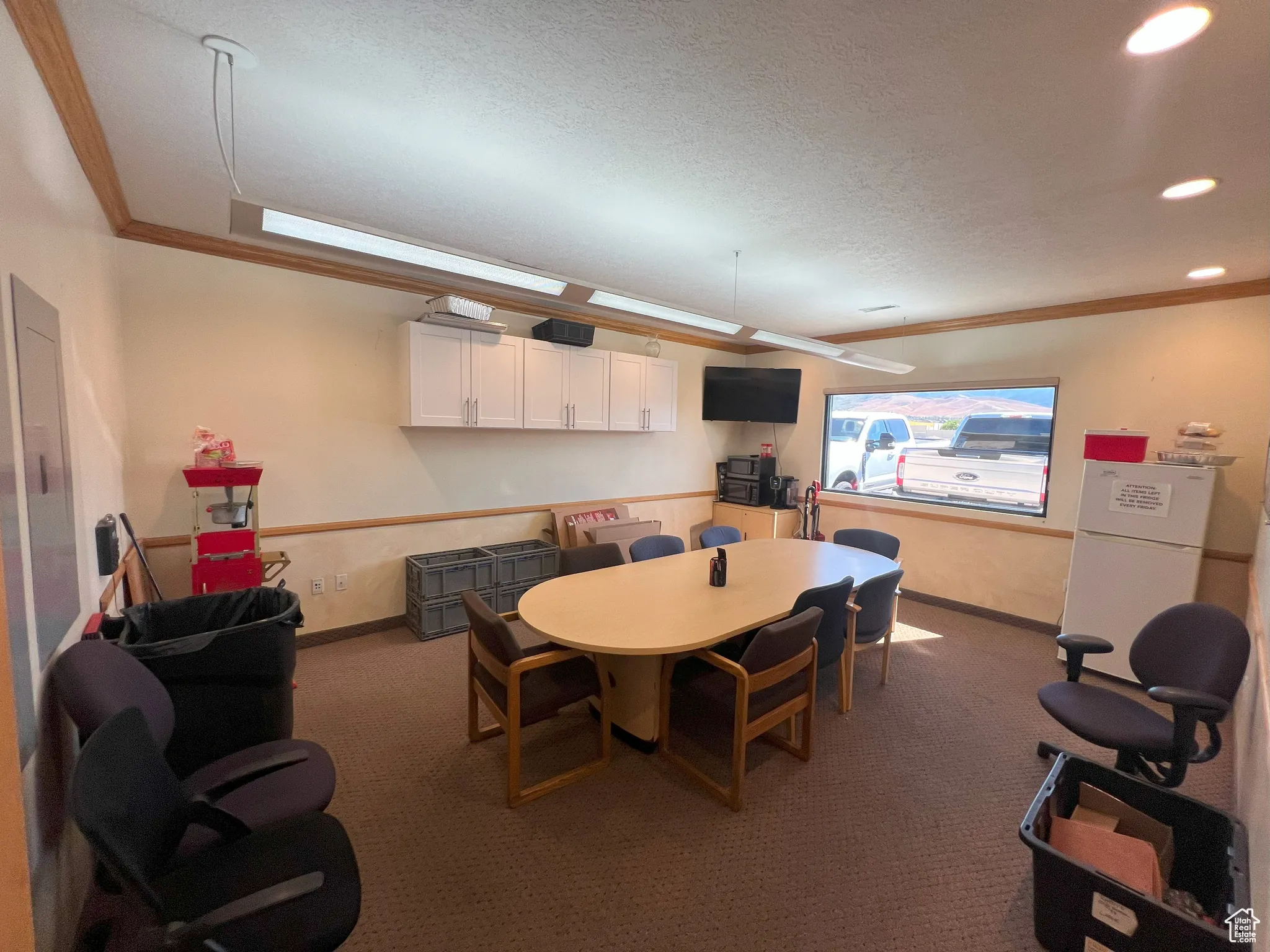 Dining room with ornamental molding, dark colored carpet, and a textured ceiling