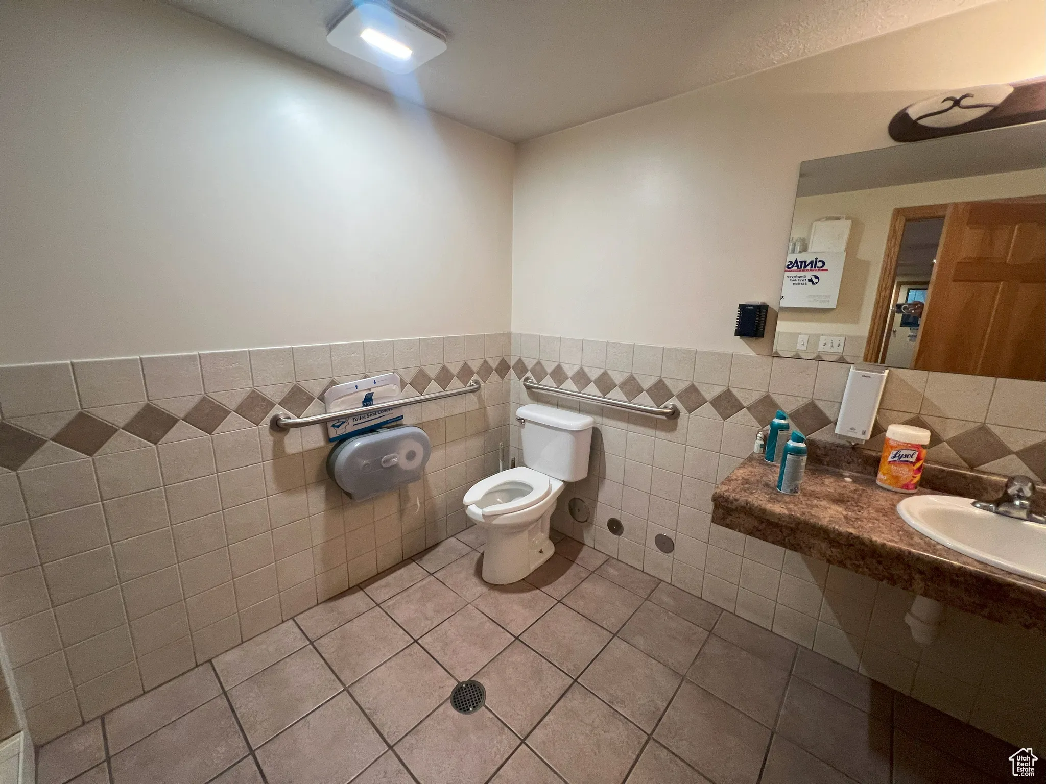 Bathroom with tile walls, tile patterned flooring, and a wainscoted wall