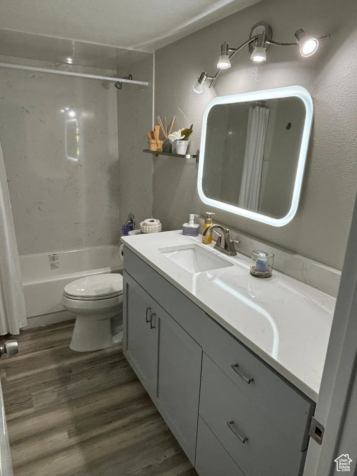 Bathroom featuring vanity, shower / bathtub combination with curtain, and dark wood-style flooring