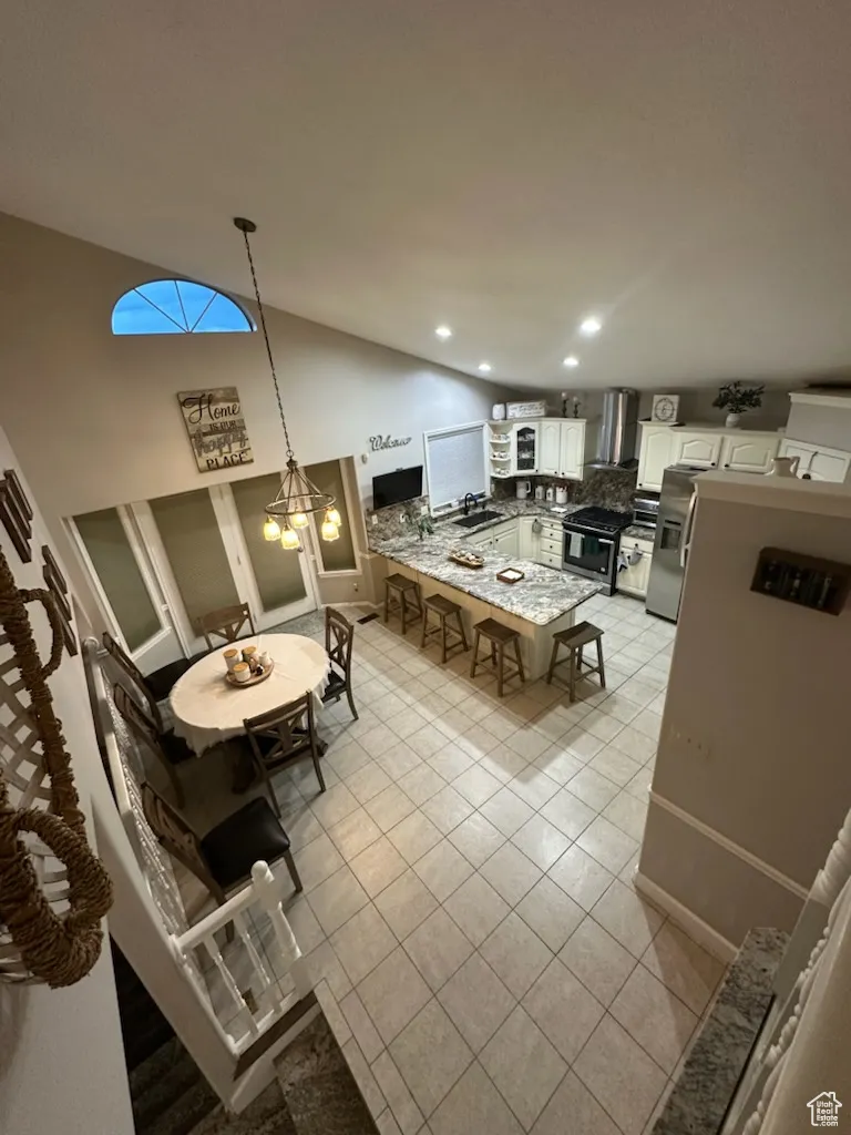 Dining room featuring light tile patterned floors, high vaulted ceiling, and recessed lighting