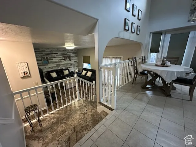 Corridor featuring tile patterned flooring, an upstairs landing, and a high ceiling
