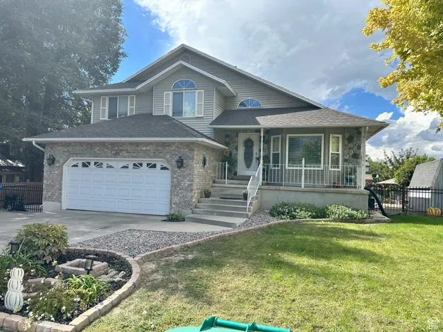 Tri-level home featuring a porch, concrete driveway, an attached garage, and a shingled roof