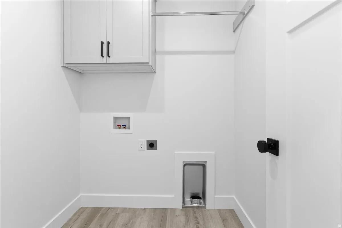 Washroom featuring electric dryer hookup, cabinet space, light wood finished floors, and washer hookup