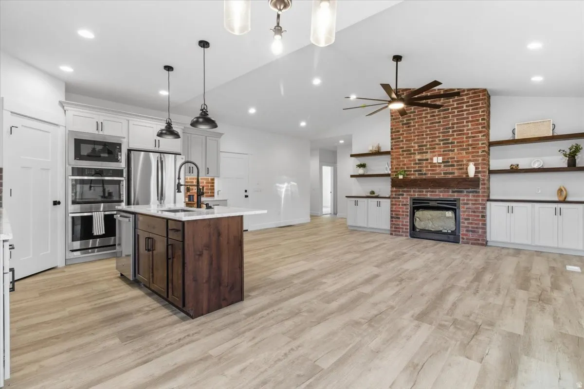 Kitchen featuring white cabinetry, decorative light fixtures, appliances with stainless steel finishes, light wood-type flooring, and recessed lighting