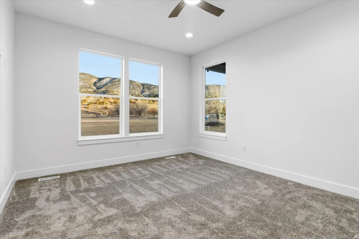 Carpeted spare room featuring a mountain view, ceiling fan, and recessed lighting