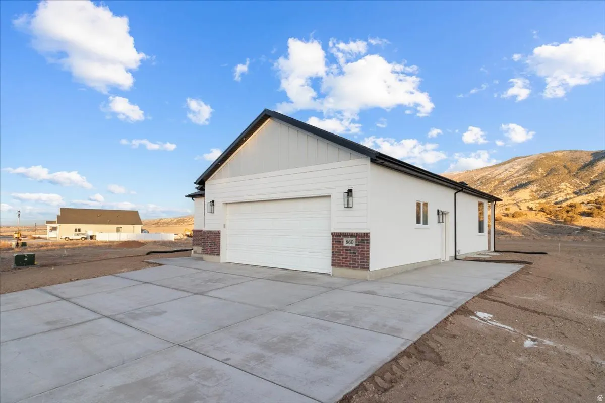 View of property exterior featuring brick siding, board and batten siding, a garage, a mountain view, and concrete driveway