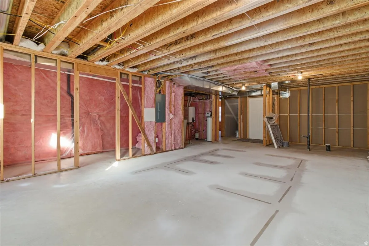 Unfinished below grade area featuring water heater and electric panel