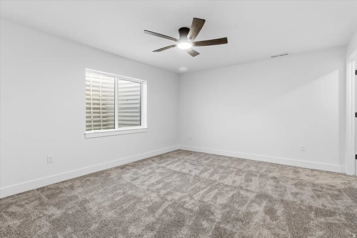 Empty room with carpet flooring and a ceiling fan