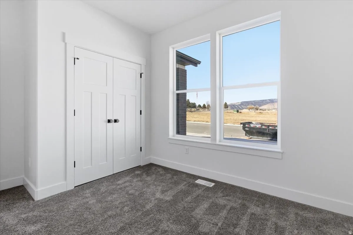 Unfurnished bedroom with dark carpet, a closet, and a mountain view