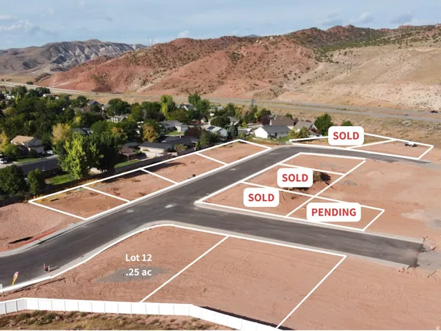 .25 acre parcel, Lot 12, featuring a paved road frontage, and mountainous backdrop