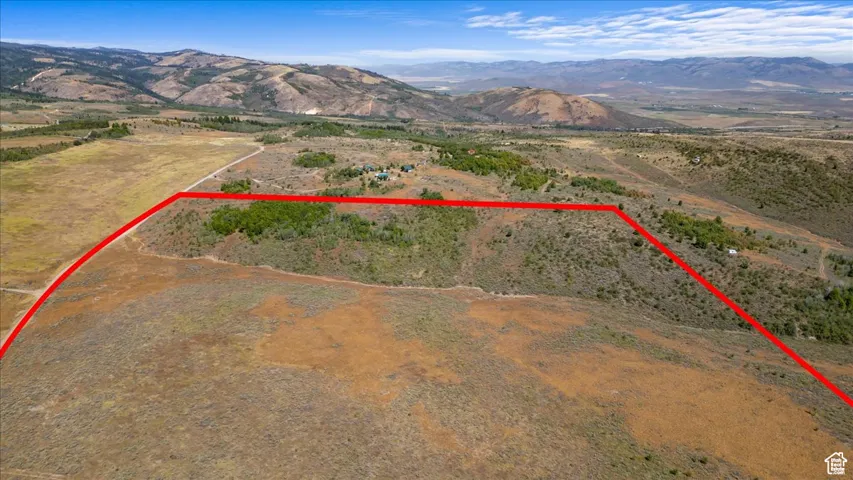 Aerial overview of property's location featuring a mountain backdrop, property parcel outlined, and rural landscape
